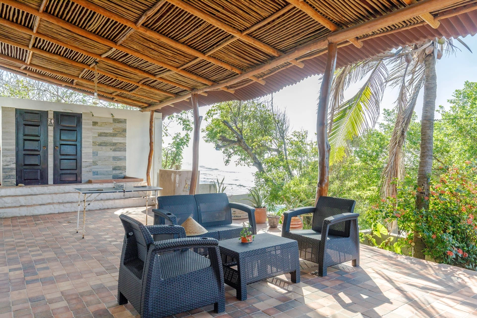 Covered patio entrance with outdoor seating and tropical greenery